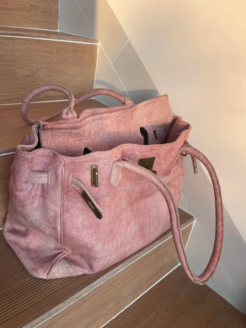 Blossom pink washed leather Firkin bag with an open top and long shoulder handles, styled on wooden stairs