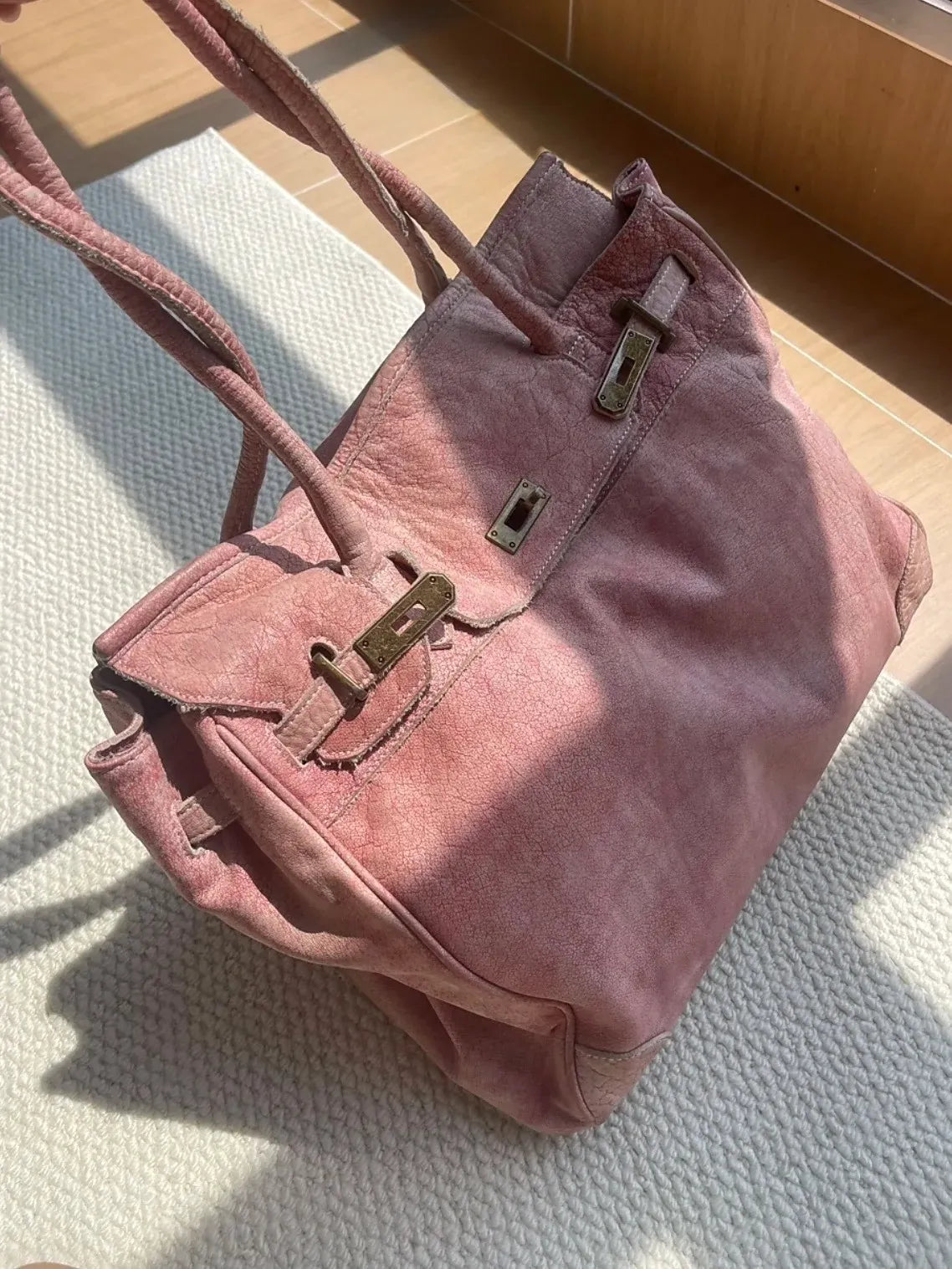 Blossom pink leather Firkin bag side view highlighting distressed leather texture and vintage metal hardware