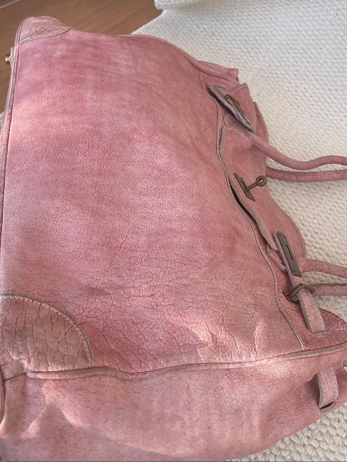 Close-up of the Blossom pink Firkin bag showing natural wrinkles, distressed full-grain leather texture and reinforced bottom corners